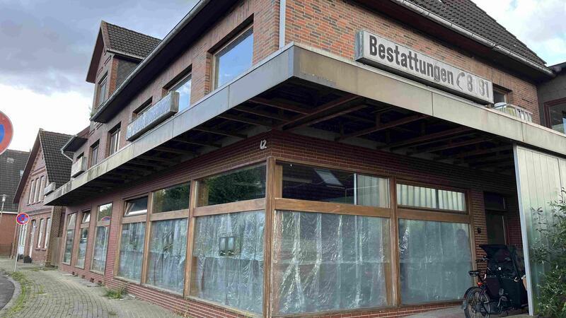 Die Fenster der Tischlerei sind verhängt, die Folie symbolisiert das Wasser der Este. In einem Fenster läuft eine Uhr - und gibt die Zeit bis zur Ausstellungseröffnung an.