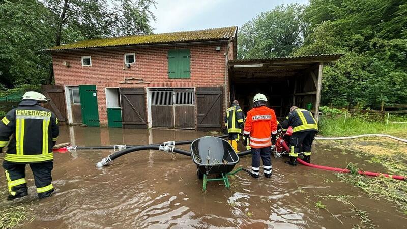 Einsatzkräfte der Feuerwehr beseitigen die Wassermassen vom Gelände eines Bauernhofs.