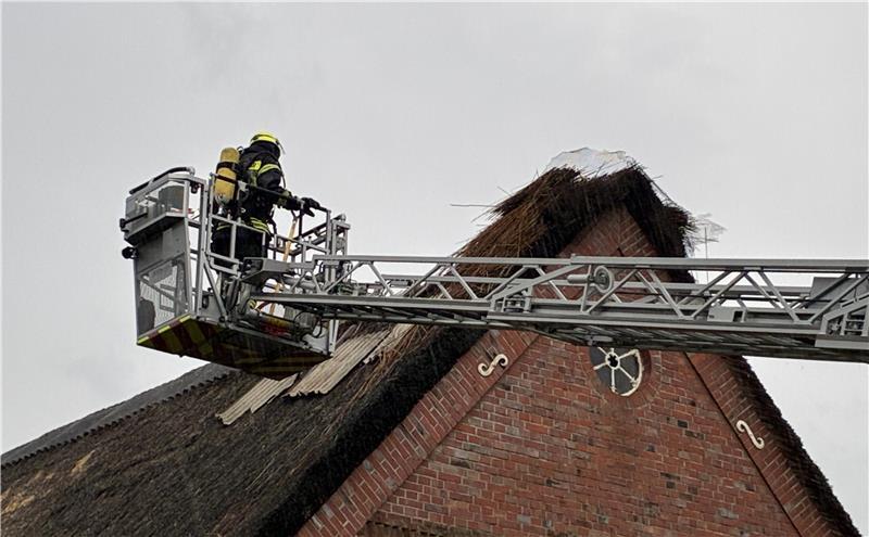 Die Feuerwehr bekämpfte den Brand mit Hilfe der Drehleiter, anschließend wurde ein Teil des Reetdachs abgedeckt.