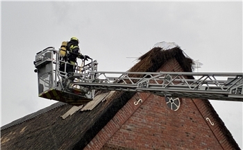 Die Feuerwehr bekämpfte den Brand mit Hilfe der Drehleiter, anschließend wurde ein Teil des Reetdachs abgedeckt.