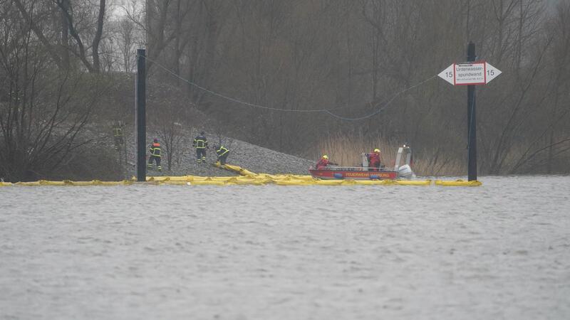 Die Feuerwehr legt Ölsperren um das gesunkene Binnenschiff im Blumensandhafen aus.