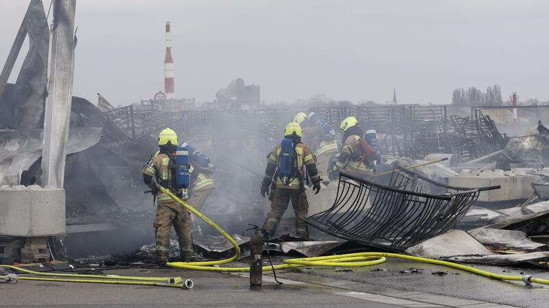 Brand in Berliner Flüchtlingsunterkunft: Neue Erkenntnisse Die Feuerwehr löscht die Brandstelle bei der Flüchtlingsunterkunft am ehemaligen Flughafen Tegel. Die Nachlöscharbeiten sind inzwischen abgeschlossen.