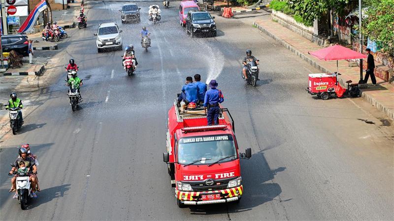 Vulkanausbruch in Indonesien: Flughäfen weiter geschlossen Die Feuerwehr spritzt Wasser auf die Straßen, um die Staubbelastung zu verringern.
