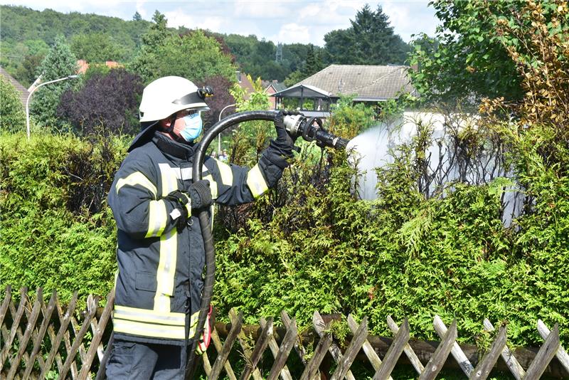 Die Feuerwehr stellt sicher, dass sich die Hecke nicht erneut entflammen kann. Fotos: Ahrens