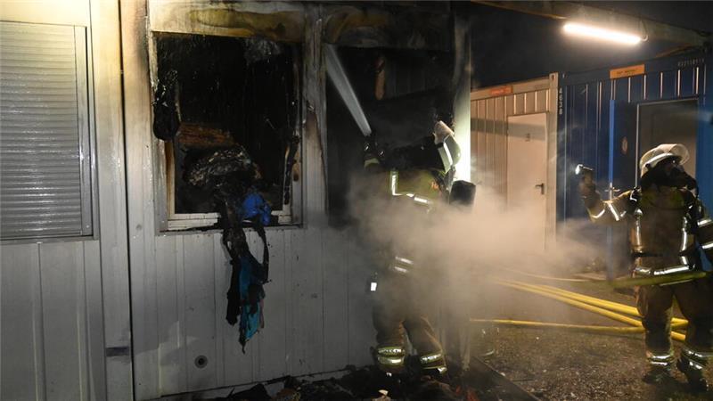 Die Feuerwehrleute bekämpfen die letzten Flammen unter Atemschutz.