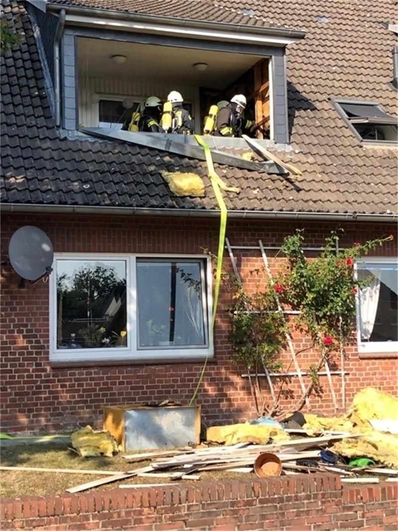 Die Feuerwehrleute entfernen Teile der Verkleidung des Wohnhauses, um dem Schwelbrand den Garaus zu machen. Foto: Höper