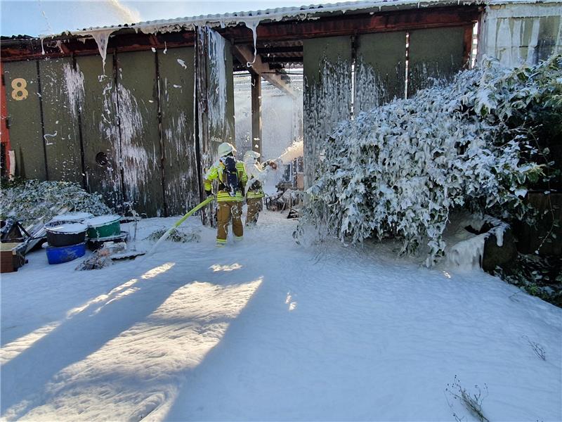 Die Feuerwehrleute fluten die Lagerhalle mit Schwerschaum, um letzte Glutnester zu ersticken - von der Drehleiter und vom Boden aus. Foto: Beneke