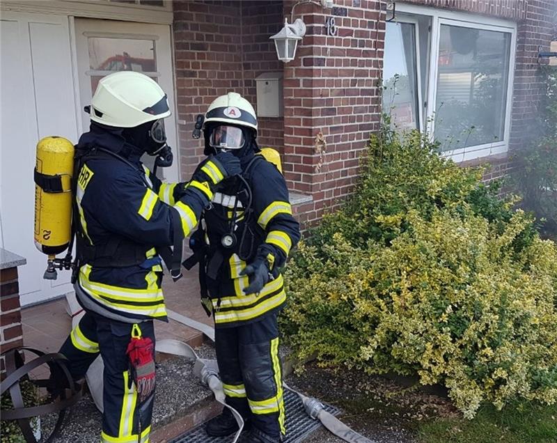Die Feuerwehrleute legen Atemschutzgeräte an, ehe sie in das verrauchte Haus gehen. Fotos: Klempahn