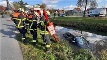 Die Feuerwehrleute müssen den Fiat und das Bushaltestellenschild in Jork aus dem Graben ziehen.