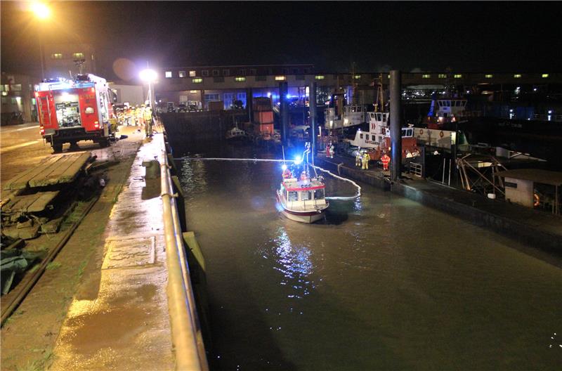 Die Feuerwehrleute verlegen eine Ölsperre im Hafenbecken des Bützflether Industriehafens. Fotos: Bube