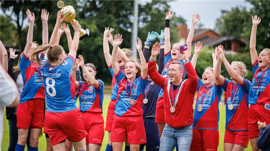 Die Fußballerinnen des FC Oste/Oldendorf II feiern mit Trainer Christopher Thielker nach der Meisterschaft auch den Pokalsieg.