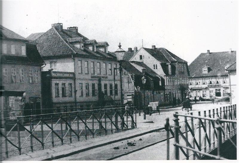 Die Gebäudezeile in den 1880er Jahren mit den Hotels „König von Schweden“ und „Zum weissen Schwan“, dazwischen das Postamt, im Vordergrund die Brücke über den westlichen Bahnhofskanal. Foto Archiv Geschichtswerkstatt Harburg