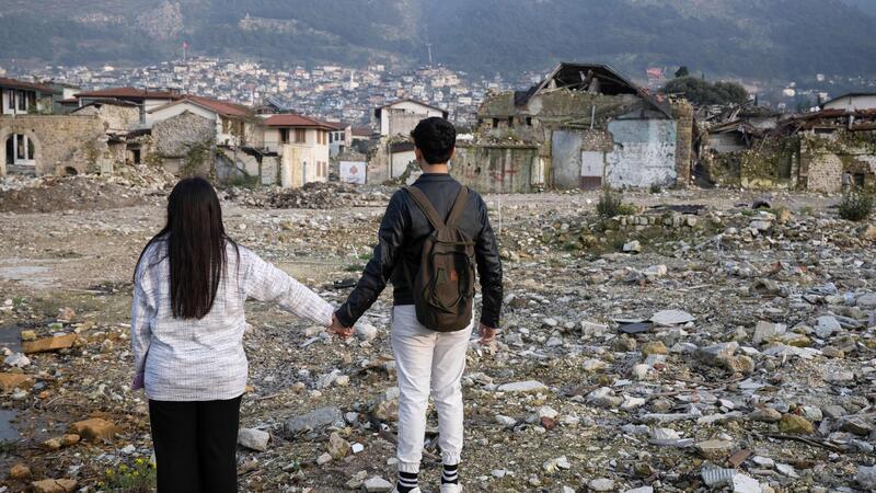 Die Geschwister Arzu (l) und Mehmet stehen in den Trümmern der Altstadt von Antakya. Beide waren bei dem Beben vor einem Jahr verschüttet worden.