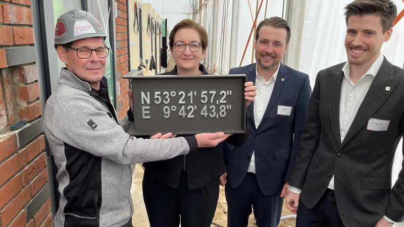 Die Grundsteinlegung für das erste Power-Townhouse-Projekt in Hollenstedt. Maurer Rainer Schmidt (von links) mit Bundesbauministerin Klara Geywitz sowie Dirk und Lars Viebrock.