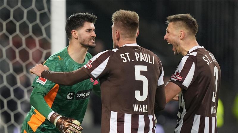 Die Hamburger Karol Mets (r-l), Hauke Wahl und Nikola Vasilj jubeln über den Sieg.
