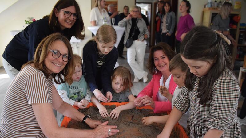 Die Harsefelder Bürgermeisterinnen Ute Kück (links) und Susanne de Bruijn freuen sich mit den Kindern über die neuen Räume und Angebote, hier mit Kinetic Sand.