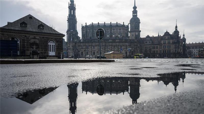 Die Hofkirche (l) und der Hausmannsturm spiegeln sich in der Altstadt auf dem Theaterplatz in einer Pfütze.