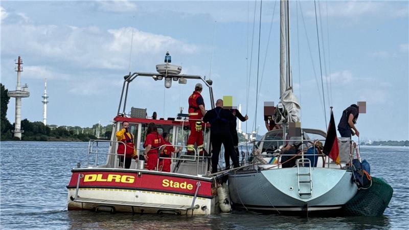 Ein Boot der DLRG Stade schwimmt neben der Segeljacht
