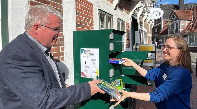 Die Jorker Büchereileiterin Christine Ottenbreit demonstriert Bürgermeister Matthias Riel die Vorteile der Abholstation in der Bürgerei.