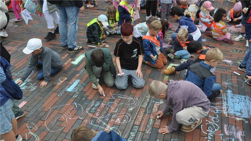 Die Kinder schreiben ihre Forderungen mit Kreide auf die Straße.