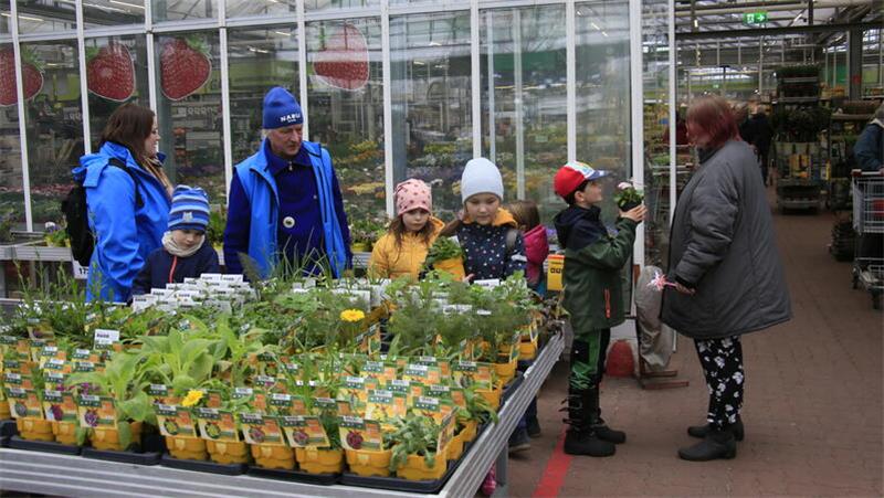 Die Kinder suchen Blumenpflanzen aus, angeleitet von Vanessa Görgens von der Stadtjugendpflege (links) und Bernd Unglaub vom Nabu.