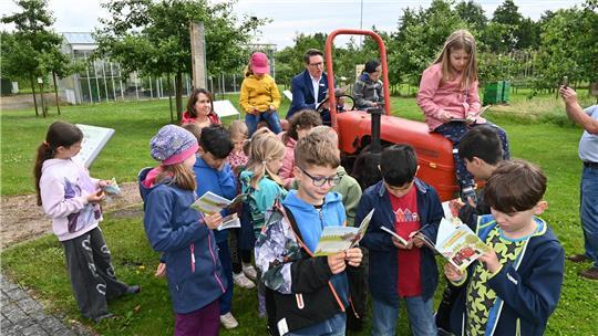 Die Klasse 2c der Grundschule Harburger Schule schaut in das Kinderbuch „Fink und Frank zeigen Dir den Apfelhof“ des Obstbauversuchsringes des Alten Landes. Sparkassen-Chef Michael Senf liest vor.