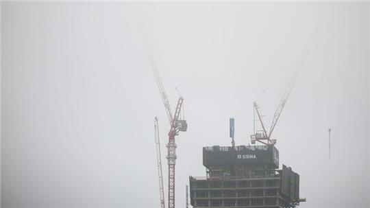 Die Kräne über der Spitze der Elbtower Baustelle in der Hafencity verschwinden im Nebel.