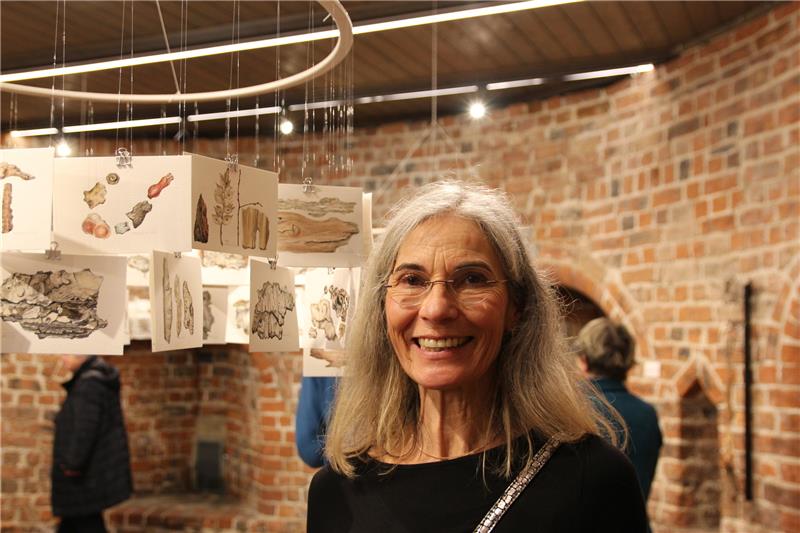 Die Künstlerin Susanne Weggen bei der Eröffnung. Wie Mobiles schweben ihre Zeichnungen im Postkartenformat an fünf Ringen von der Decke und bewegen sich bei jedem Lufthauch. Fotos: Richter