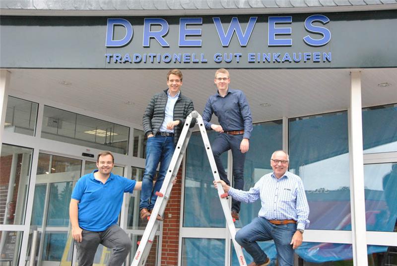 Die Leiter des Bauarbeiters nutzen die Juniorchefs Oliver und Christian Drewes, Marktleiter Tobias Bäck und Seniorchef Claus Drewes (von links) für ein Gruppenfoto. Fotos: Lohmann