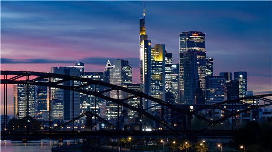 Die Lichter der Bankenskyline von Frankfurt leuchten in der Abendstimmung.