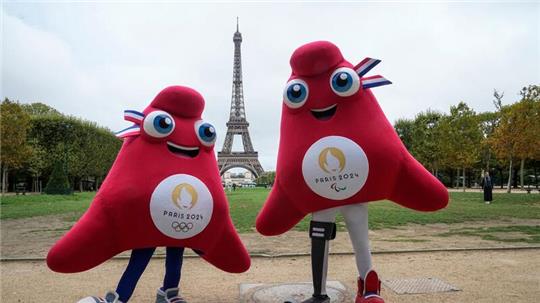 Die Maskottchen der Olympischen (l) und Paralympischen Spiele in Paris stehen vor dem Eiffelturm.