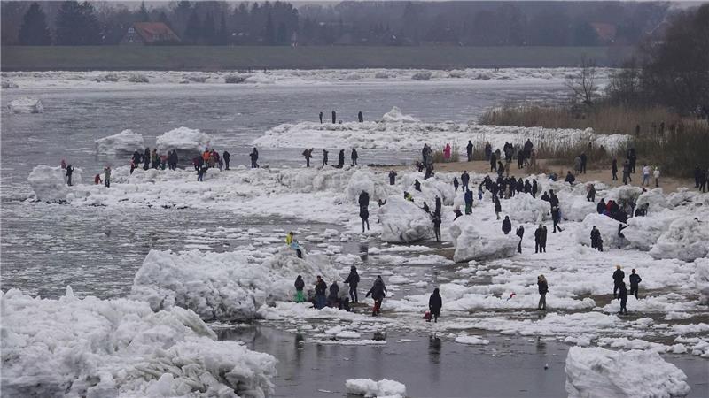 Die Menschen wandern zwischen den Eisblöcken umher. 