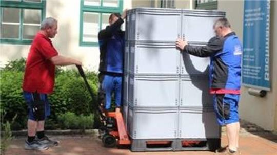 Die Mitarbeiter der Spedition Meyer transportieren die Boxen mit den Museumsobjekten vorsichtig aus dem Museumsgebäude.