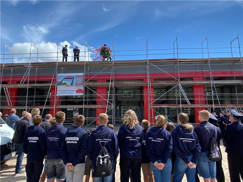 Die Mitglieder der Jugendfeuerwehr überreichten Ortsbrandmeister Sebastian Junge und seinem Stellvertreter Maik Bube die Richtkrone. Diese übergaben sie an denZimmermann Eric Wittkowski vom Bauunternehmen Menke. Foto: Stadt Stade