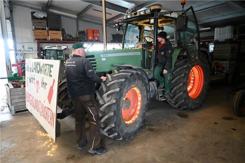 Die Obstbauern Gerd König und Sören Baumgarten von „Land schafft Verbindung“ schmücken ihren Traktor mit Lichterketten und einem Protestplakat (von links). Foto: Vasel