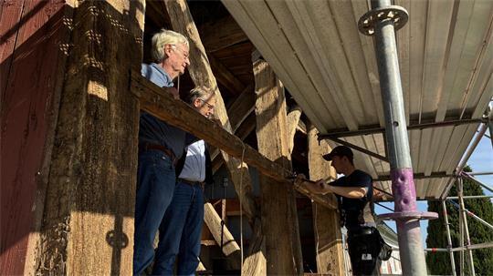 Die Pastoren Uwe Junge und Olaf Prigge schauen Zimmermann Patrick Holst bei den Sanierungsarbeiten am Turm von St. Johannes in Neuenkirchen zu (von links).