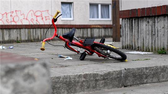 Ein Kinderfahrrad liegt in einem Aufgang zu einem Plattenbau.