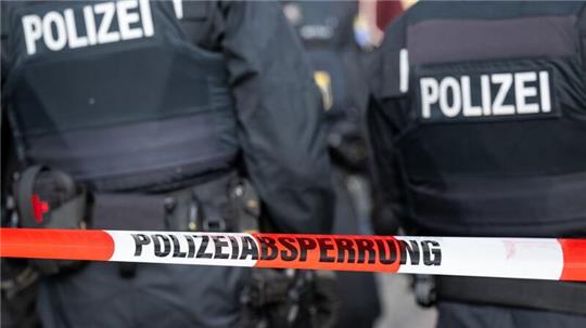 Polizisten stehen hinter einem Polizei-Flatterband.