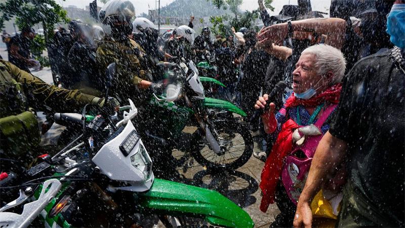 Die Polizei setzt während eines Marsches anlässlich des 7. Jahrestags des sozialen Aufstands in Chile im Jahr 2019 einen Wasserwerfer ein, um Demonstranten zu vertreiben, die gegen geplante Ausgabenkürzungen der Regierung protestieren.