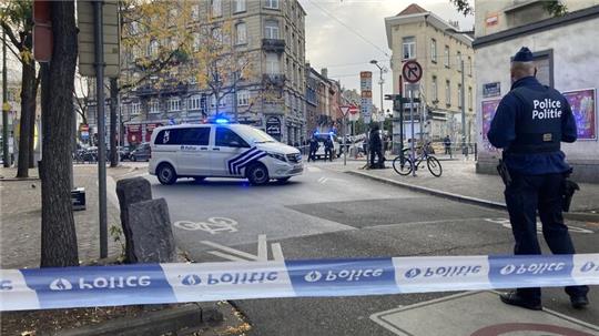 Die Polizei sperrt eine Straße, während ein Polizist hinter Absperrband Wache steht.