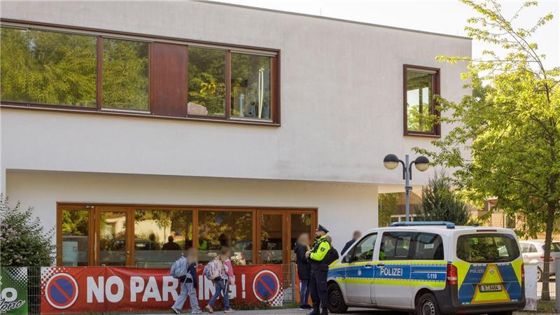 Die Polizei steht vor einer Grundschule im Berliner Bezirk Spandau, während Schüler am Morgen zur Schule kommen. 