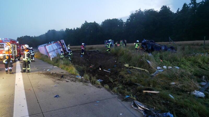Unfall auf A1: Lkw schleudert Auto auf Feld – 200.000 Euro Schaden Mehrere Einsatzkräfte der Feuerwehr räumen die Unfallstelle, im Hintergrund ist ein umgekippter Lastwagen zu sehen.