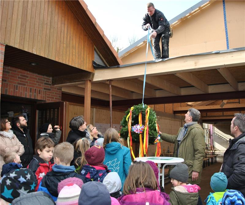 Die Richtkrone wird hochgezogen: Viele Kinder feiern mit beim Richtfest der neuen Mensa zwischen der Eichhörnchen-Grundschule und der DRK-Kindertagesstätte Dollern. Foto Lohmann