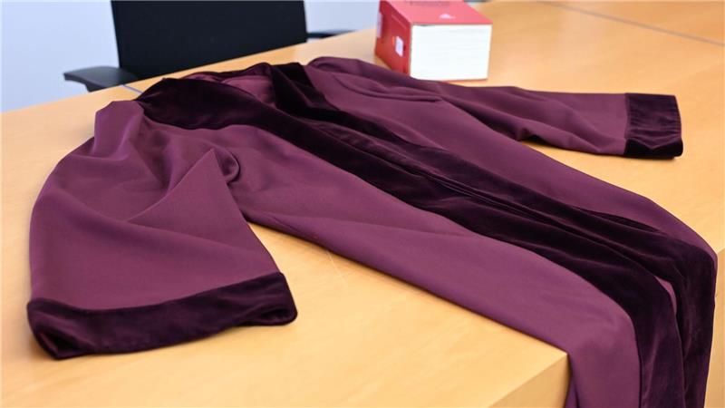 Die Robe zeichnet sich durch den tiefen Rot-Ton und den Samtbesatz an Ärmeln und Kragen aus. 