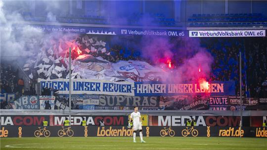 Die Rostocker Fans halten Banner mit der Aufschrift „Rügen unser Revier - Hansa unser Leben“ und zünden Pyrotechnik.