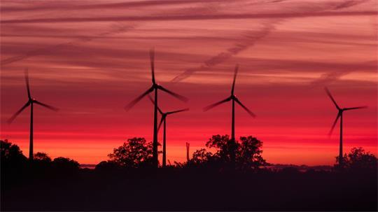 Die Rotoren von Windkraftanlagen drehen sich kurz nach Sonnenuntergang in einem Windpark in Mecklenburg-Vorpommern.