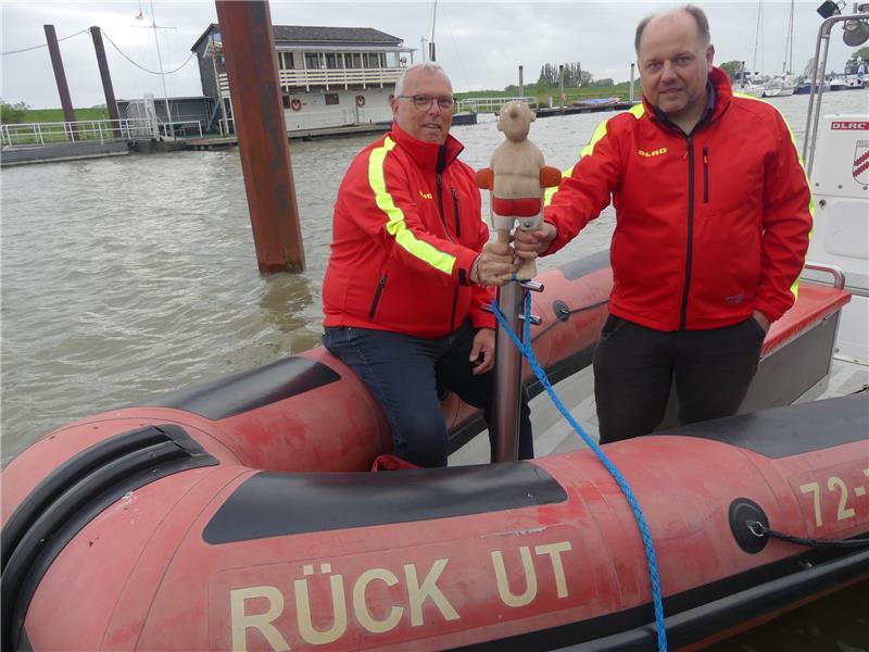 Die „Rück Ut“ muss ersetzt werden. Torsten Hilck (links) und Claus Fastert von der DLRG hoffen auf gute Gebote für das Unikat von Bildhauer Jonas Kötz, der damit die Spendenaktion unterstützt. Foto: Knappe