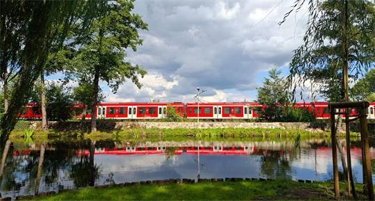 Die S-Bahnlinie 5 spiegelt sich in einem Agathenburger Schlossteich.