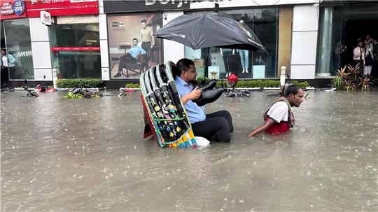 Die Schuhe bleiben trocken: Ein Mann lässt sich in Bangladesch in einer Rikscha durch eine überflutete Straße fahren. 