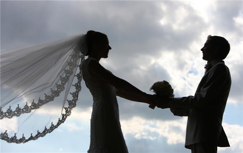 Die Silhouette eines frisch vermählten Hochzeitspaares zeichnet sich im Gegenlicht ab. Foto: Patrick Pleul/dpa-Zentralbild/dpa